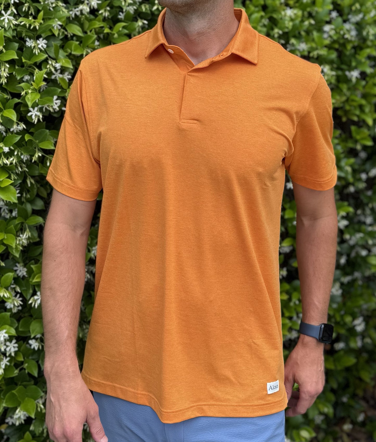 Man wearing Alon's Satsuma orange Bond Polo with company word mark patch