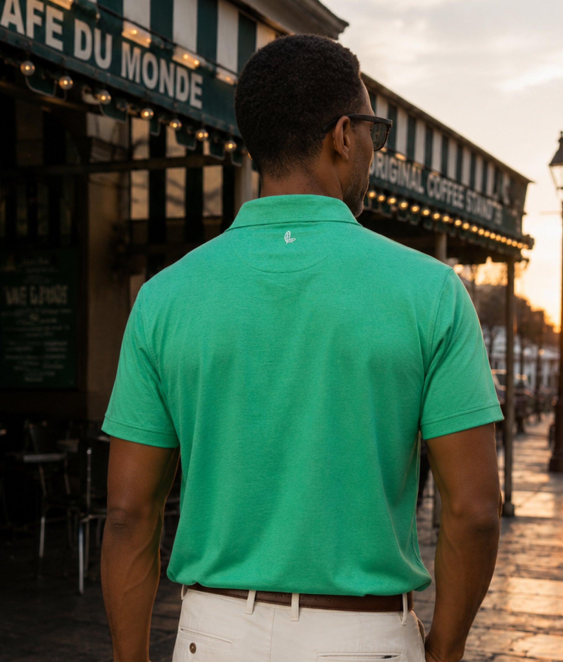 Man wearing a green polo shirt standing in front of Cafe du Monde.