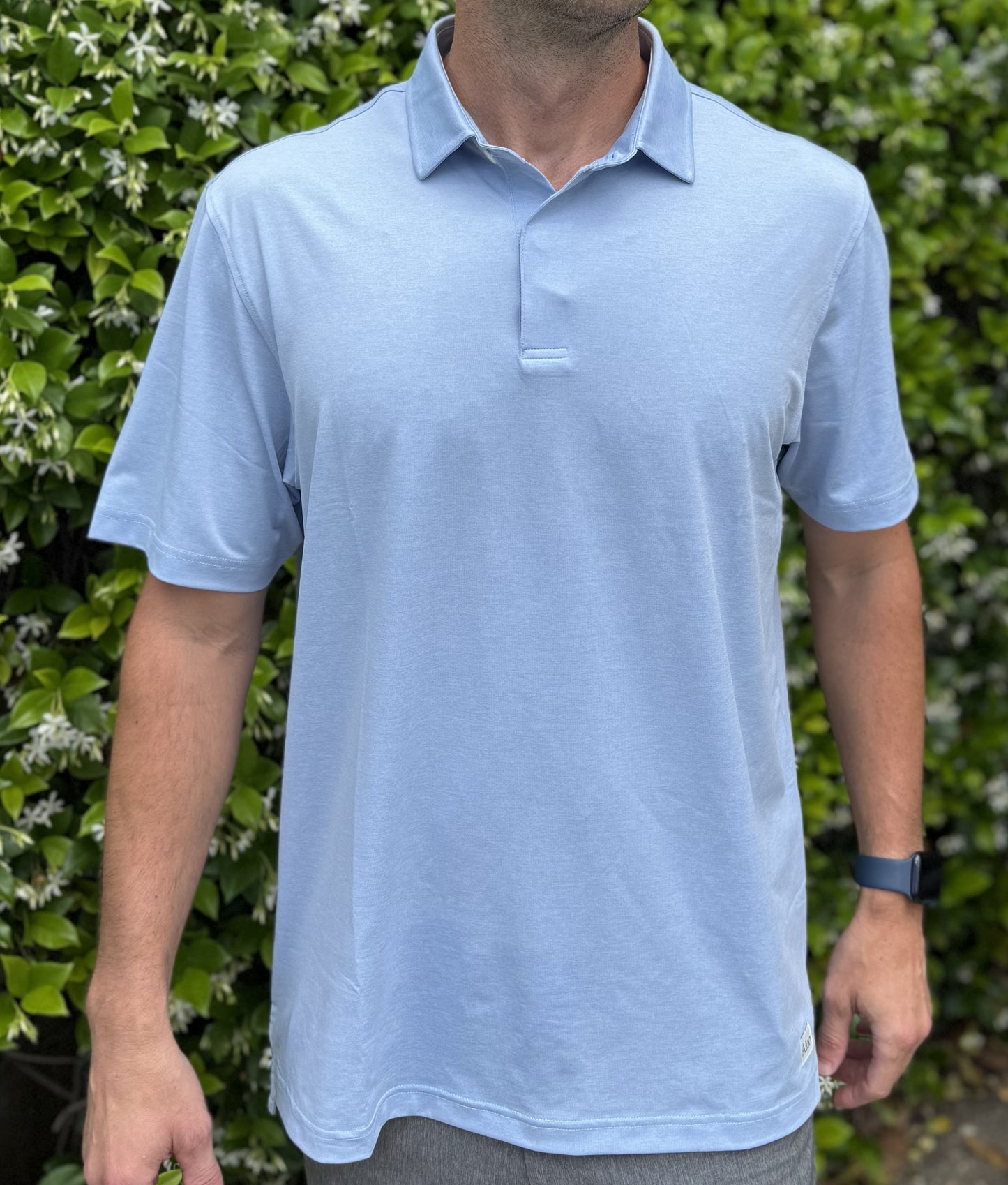 Man wearing Alon's Porch Ceiling light blue Bond Polo with company word mark patch