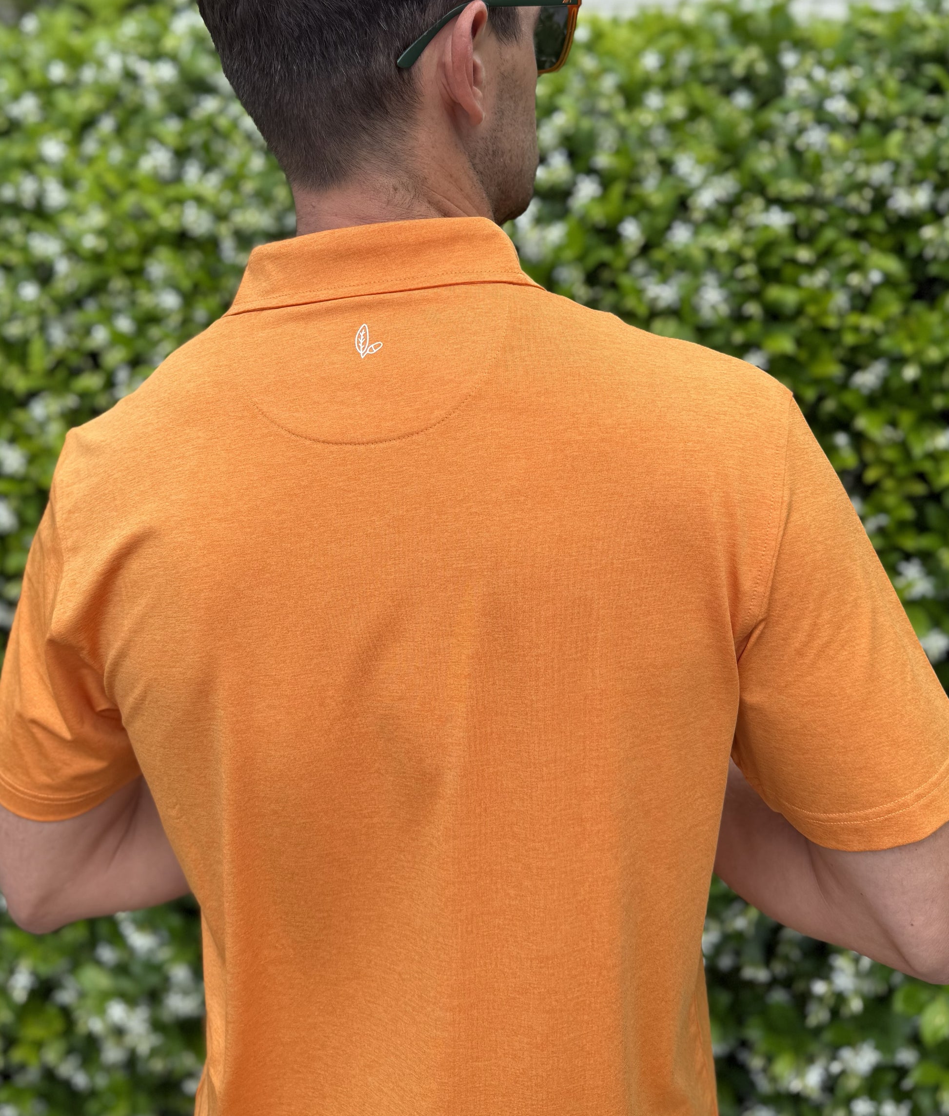 Man wearing Alon's Satsuma orange Bond Polo with leaf and acorn heat transfer logo.