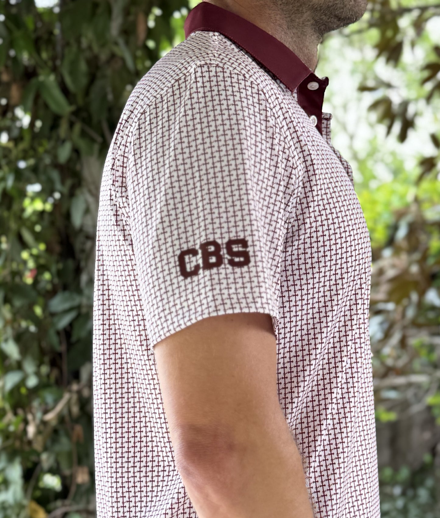 Crimson colored Lasallian cross patterned polo over white fabric with CBS heat transfer logo detail.