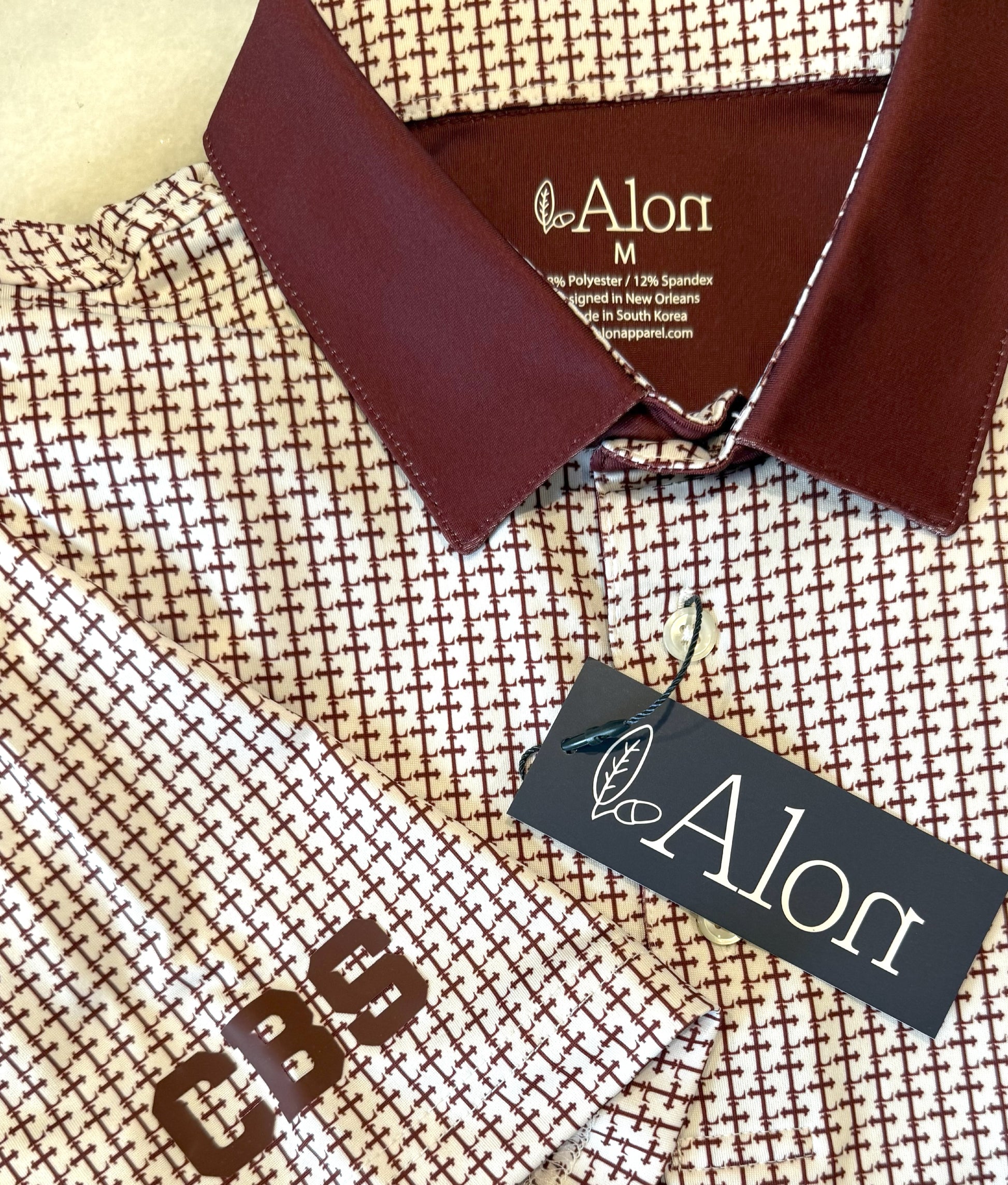 Crimson colored Lasallian cross patterned polo over white fabric.