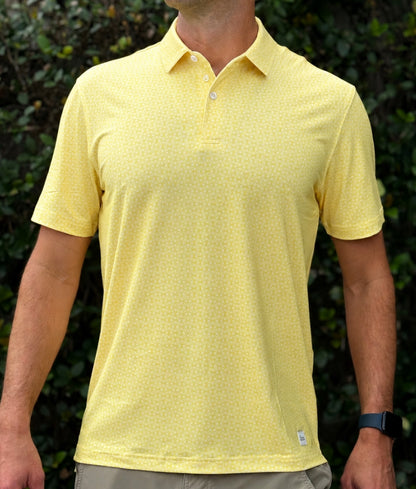 Person wearing a yellow patterned polo shirt with a blurred green background