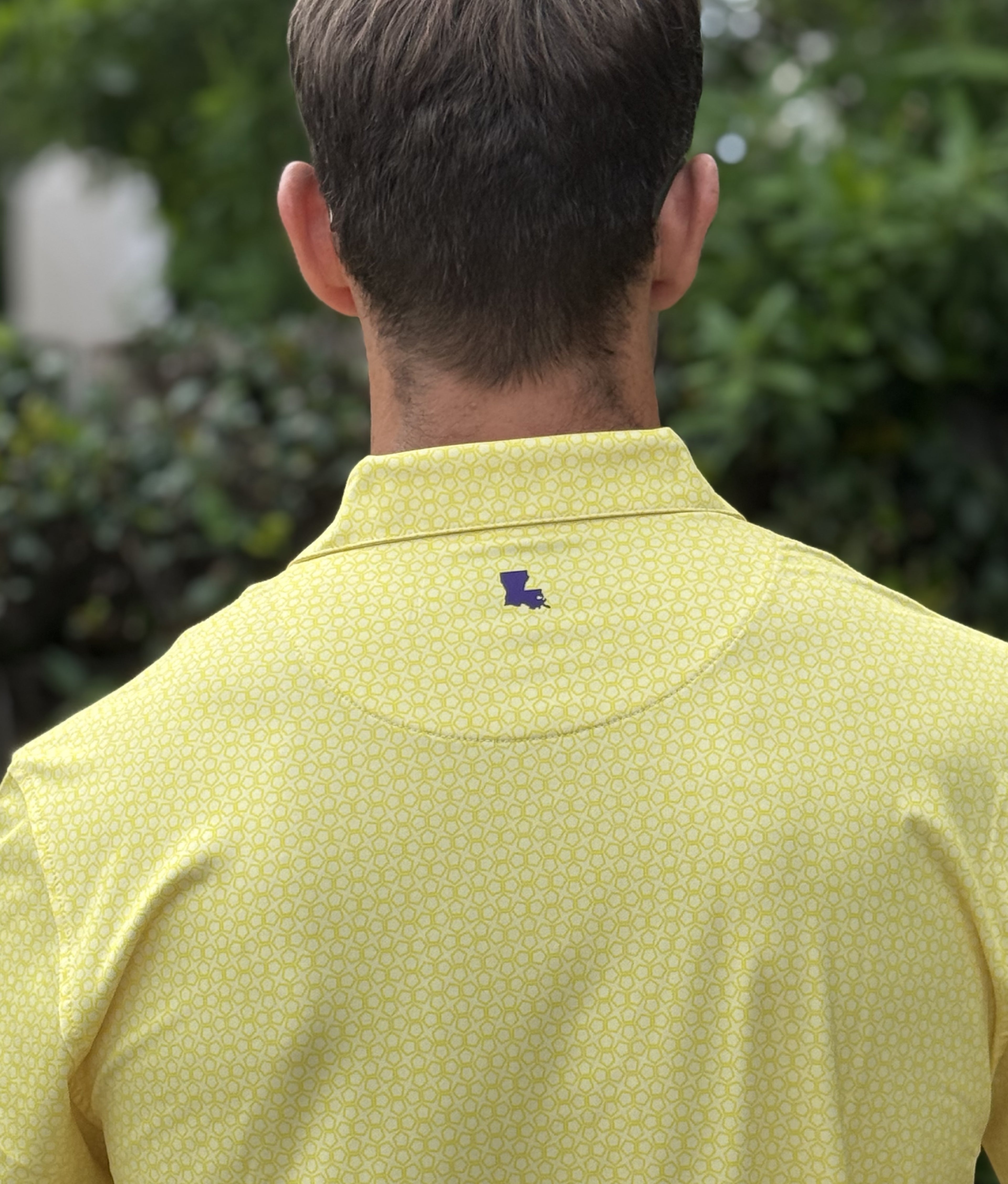 Man wearing a yellow patterned polo shirt with a purple Louisiana logo beneath the collar