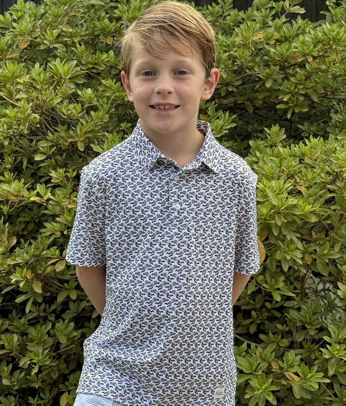A young boy wearing a New Orleans Saints patterned polo